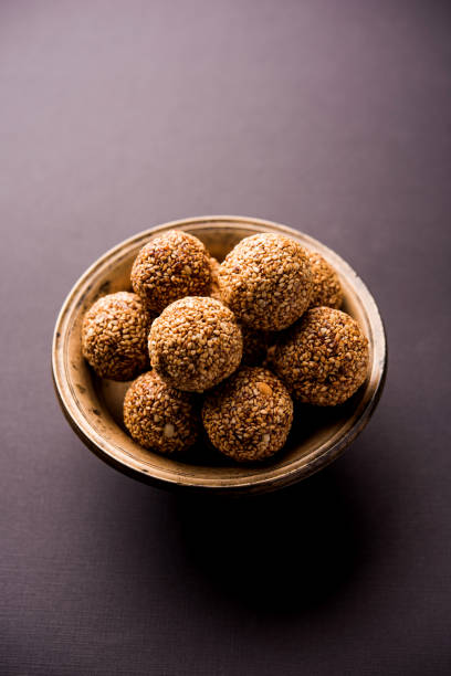 bolas de tilgul laddu o til gul de makar sankranti, es un alimento sano, hecho con sésamo, maní picado y jaggery. sirve en un tazón. detalles de la demostración de enfoque selectivo. - peanut bowl nut circle fotografías e imágenes de stock