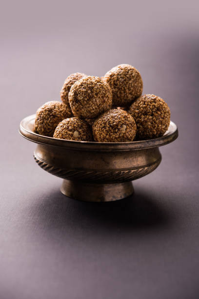 bolas de tilgul laddu o til gul de makar sankranti, es un alimento sano, hecho con sésamo, maní picado y jaggery. sirve en un tazón. detalles de la demostración de enfoque selectivo. - peanut bowl nut circle fotografías e imágenes de stock