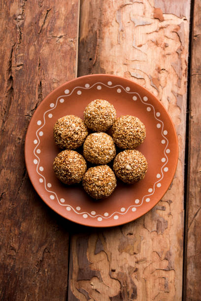 tilgul laddu o til gul palle per makar sankranti, è un cibo sano fatto con sesamo, arachidi schiacciate e jaggery. servito in una ciotola. messa a fuoco selettiva che mostra i dettagli. - peanut bowl nut circle foto e immagini stock