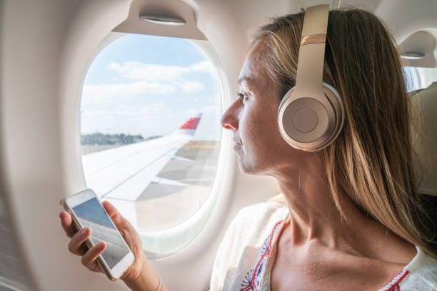 istock Young woman in airplane using mobile phone during flight 1087422302