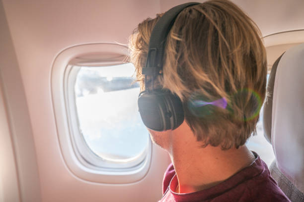 istock Young man in airplane looking through window 1087426732