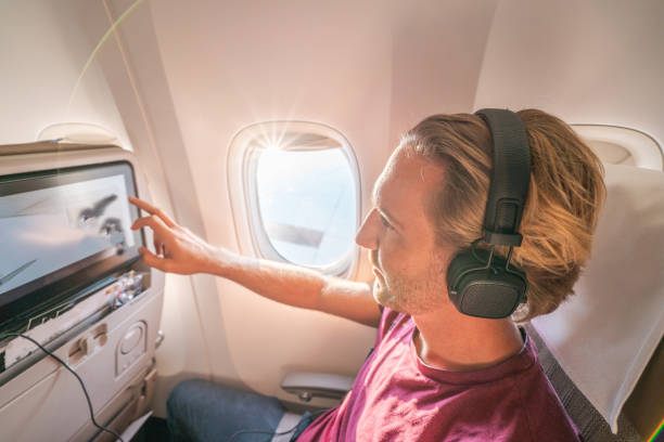 istock Young man in airplane using onboard entertainment 1087429234