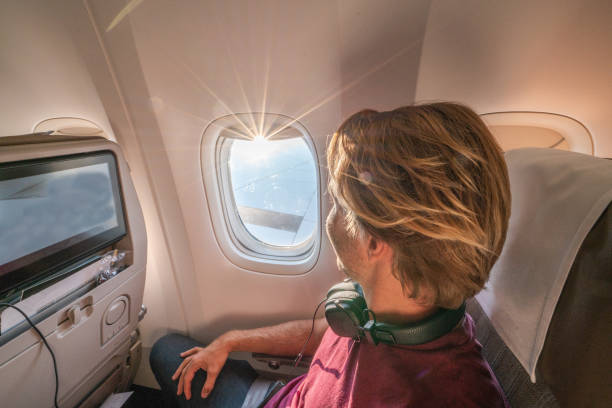 istock Young man in airplane using onboard entertainment 1087429468
