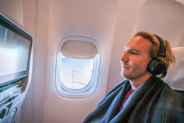 istock Young man in airplane using onboard entertainment 1087432062