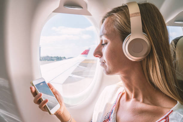 istock Young woman in airplane using mobile phone during flight 1087432276