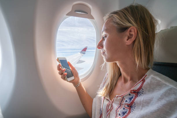 istock Girl in airplane using mobile phone 1087434238