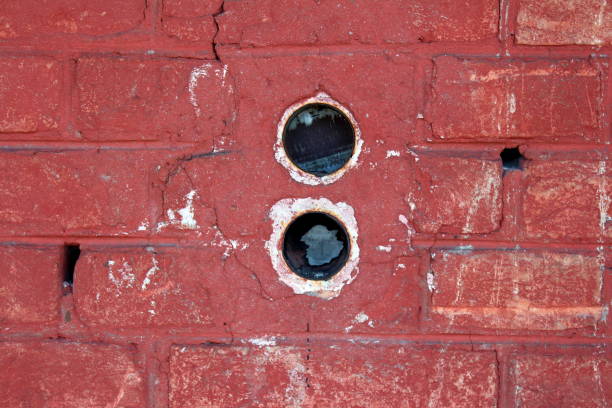 istock Two round electrical outlet boxes without wires mounted inside dilapidated red brick wall 1087435760