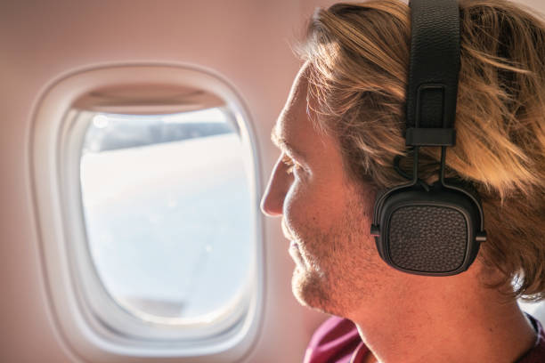 istock Young man in airplane looking through window 1087441384