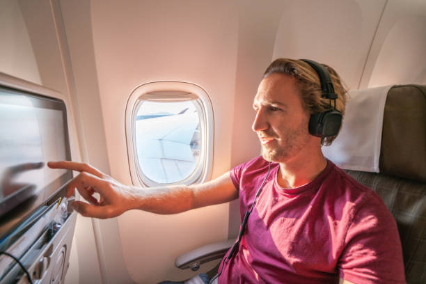 istock Young man in airplane using onboard entertainment 1087441386