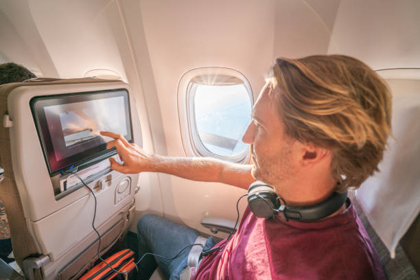 istock Young man in airplane using onboard entertainment 1087443494