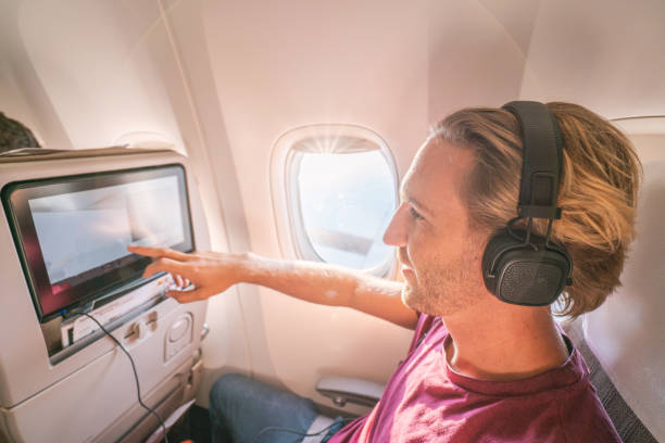 istock Young man in airplane using onboard entertainment 1087444658