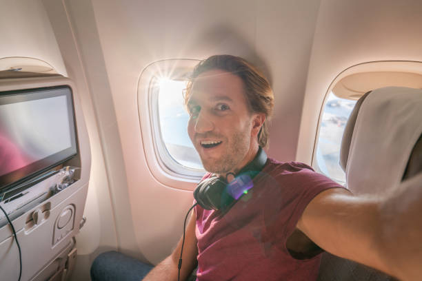 istock Young man in airplane takes mobile phone selfie portrait during flight 1087444792