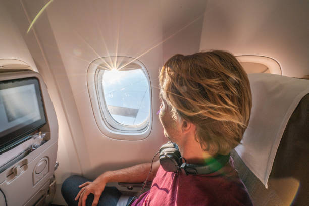 istock Young man in airplane looking through window 1087445628