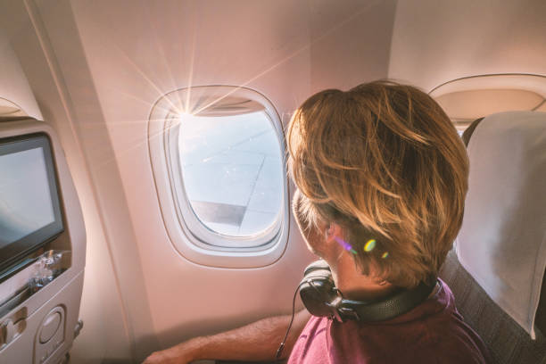 istock Young man in airplane looking through window 1087447304