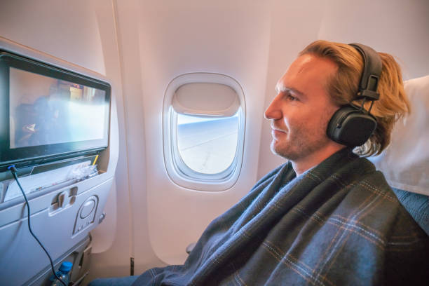 istock Young man in airplane using onboard entertainment 1087448674