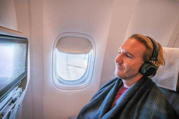 istock Young man in airplane using onboard entertainment 1087448890