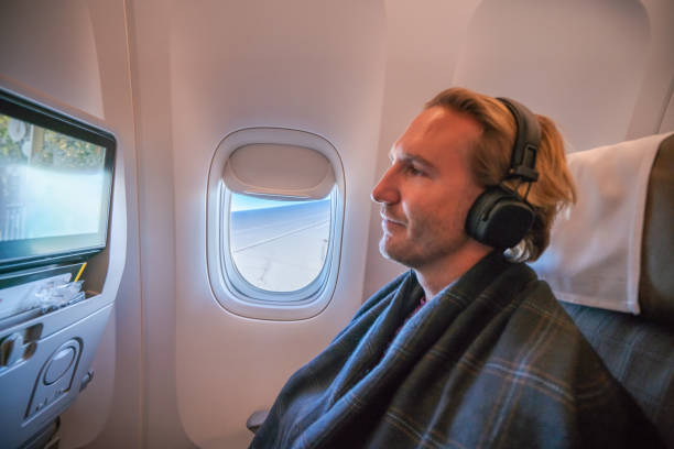istock Young man in airplane using onboard entertainment 1087448894