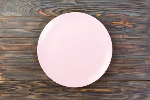 istock Directy above Empty rose matte plate on dark wooden background 1087462594