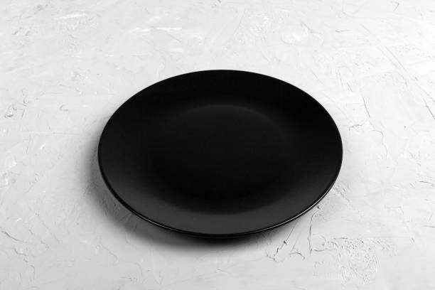 istock Top view of matte round empty black plate on dark cement background copy space for you design. Perspective view 1087462642