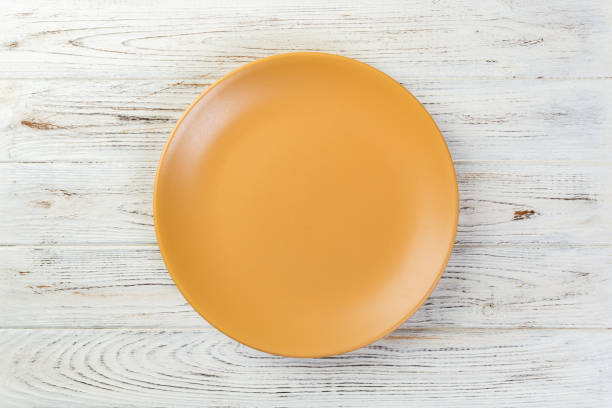 istock Directy above Empty yellow matte plate on white wooden background 1087464352