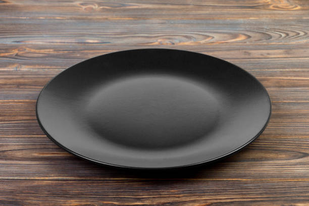 istock Perspective view. Empty dark matte dish for dinner on wooden background 1087464372