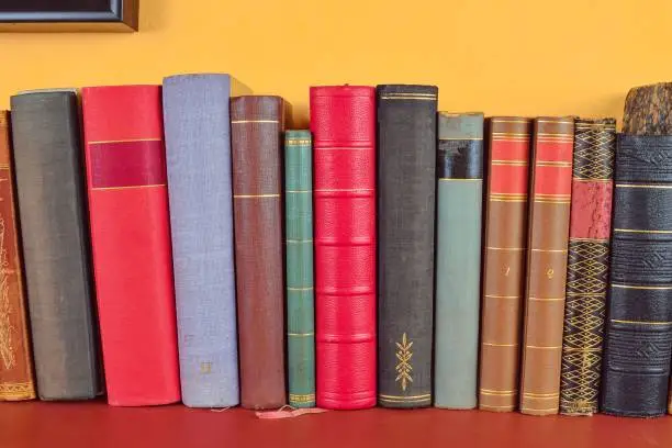 Wooden shelf with historic,decorated, vintage books. Old books on yellow and claret background.