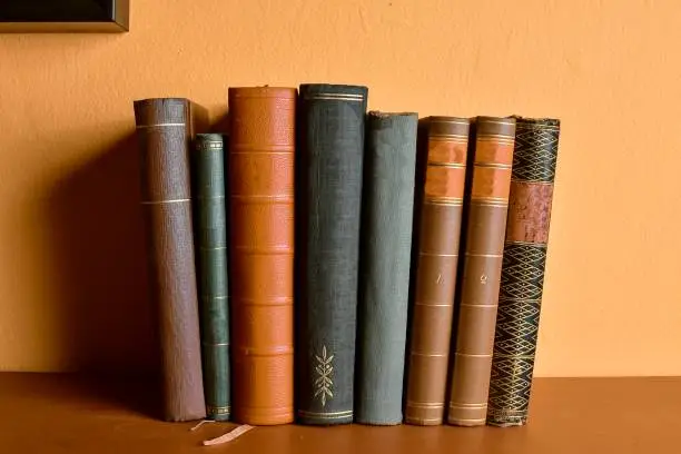 Row of old  bound books. Antique books on yellow and claret background.