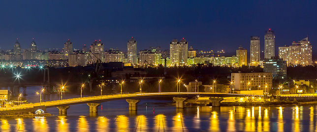 Kyiv (Kiev) city, the capital of Ukraine at night beside the Dnipro (Dniepr) river with reflection in water