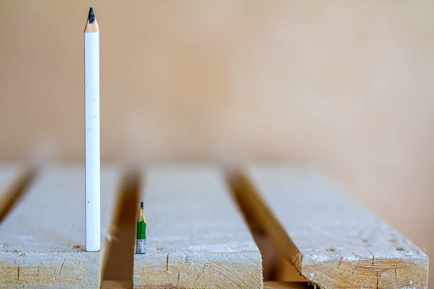 istock Wooden boards table top with one small and one big pencil 1087494232