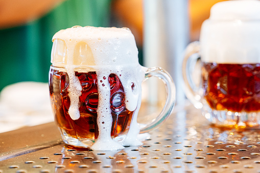 Fresh beer with foam from tap in a german traditional mug