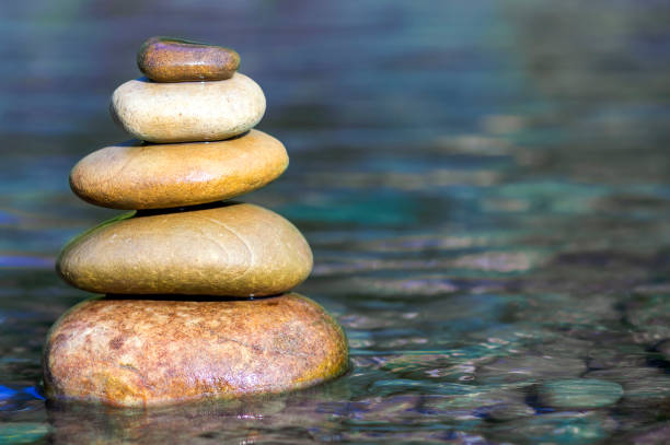 istock Stack of stones balancing on top in blue water of the river 1087501046