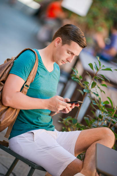 istock Caucasian boy is holding cellphone outdoors on the street. Man using mobile smartphone. 1087504652