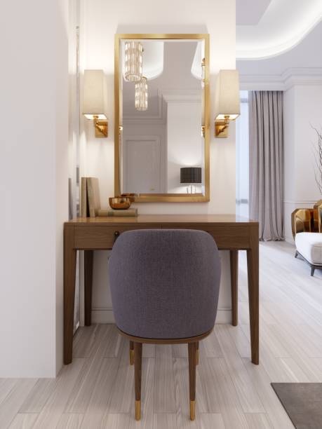 istock Designer working and dressing table made of wood with a mirror in a gilded frame and glowing sconces on the wall in the suite. 1087506010