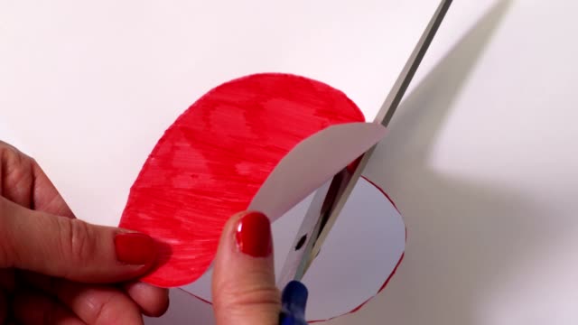 Woman cutting out red heart shape
