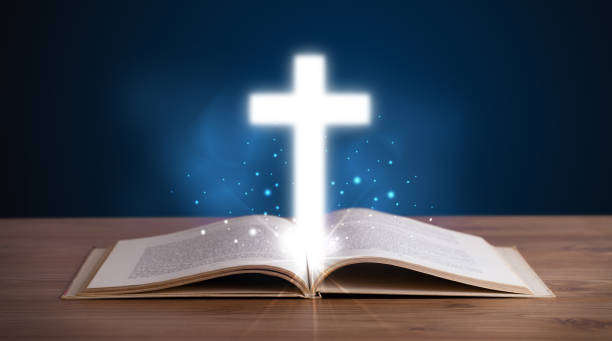 istock Open holy bible with glowing cross in the middle 1087508492