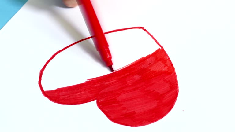 Woman coloring red heart shape close up