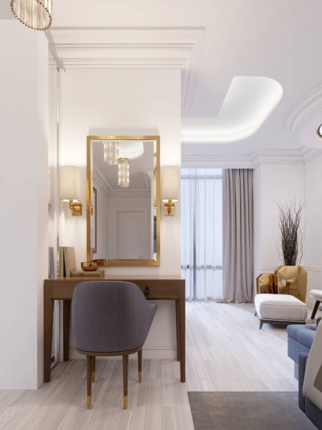 istock Designer working and dressing table made of wood with a mirror in a gilded frame and glowing sconces on the wall in the suite. 1087510328
