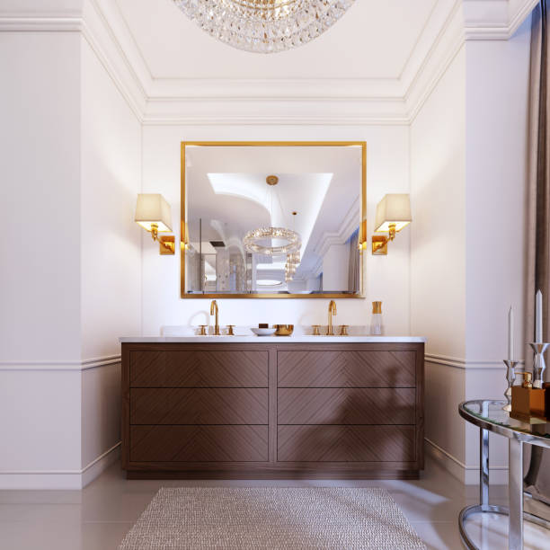 Modern wooden vanity with a mirror in a gold frame and sconces on the wall, a low table with decor and a rug with a chandelier.