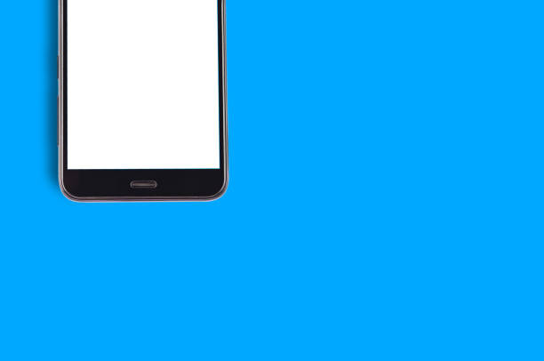 istock Single black smartphone with isolated blank white screen on blue background with copy space for your text. Top view 1087517566