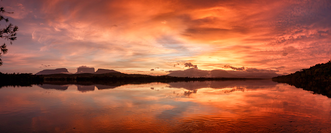 Early  morning panoramic view at sunrise of the Carrao river in the Canaima National Park, Venezuela. Group of tepuis, from left to right: Kurun, Kusary, Kurawaik and Tok Pochik. Canaima is a world known place for the beauty of nature and countless waterfalls. Canaima is visited for tourist all around the world during all year round. During rainy season navigation on the Churun river is possible to visit the Angel falls, the tallest waterfall in the world with 976 mt of water free fall.