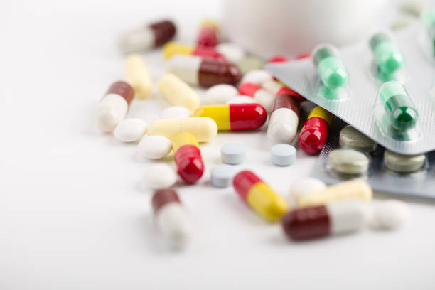Assorted pharmaceutical medicine pills, tablets and capsules over white background.