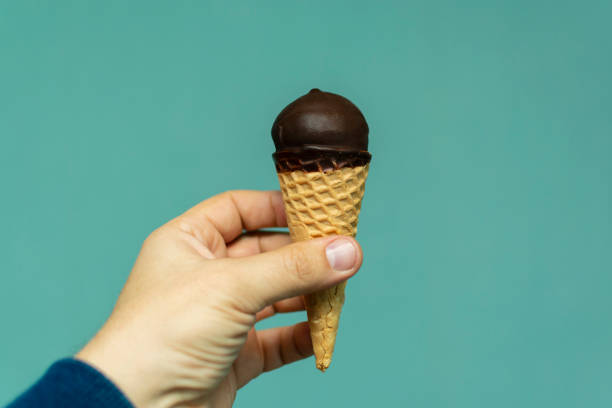 istock ice cream in the cone and chocolate coating on a blue background in hand 1087534008
