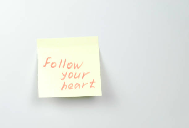 istock Note on yellow sticker paper sheets with motivation words follow your heart. 1087534854