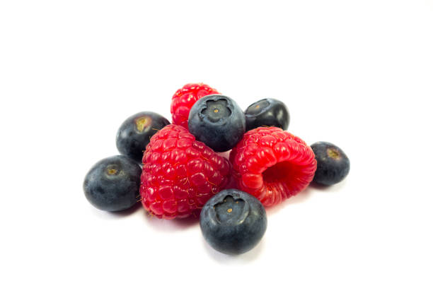 Top view of raspberries in the plate on background of blueberries. Fresh berries assortment. Ripe and juicy fresh raspberries close-up. Conceptual food picture for illustration projects.