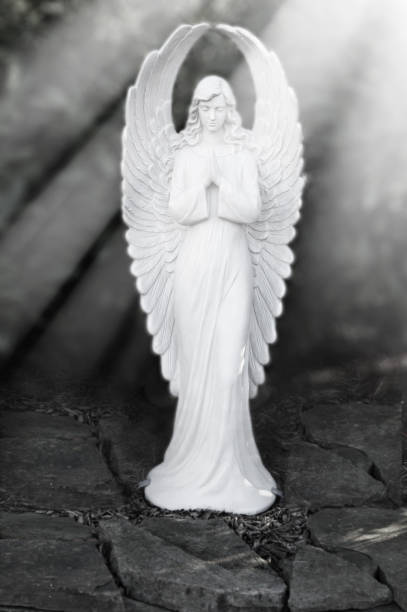 istock Praying white angel surrounded by sun rays in black and white 1087544170