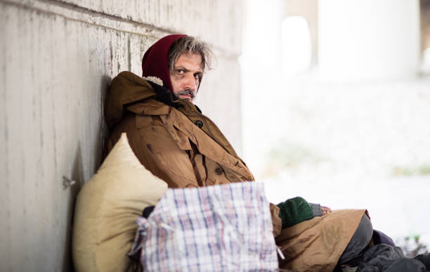 istock A side view of homeless beggar man sitting outdoors, leaning against a wall. Copy space. 1087549810