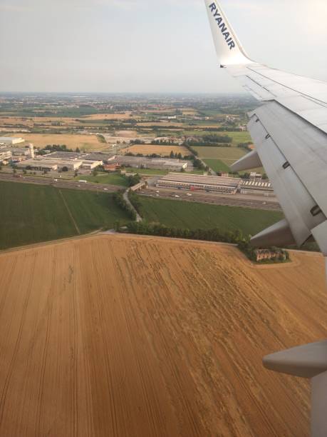 an aerial view of the bergamo countryside, with plowed and planted fields, industrial warehouses and streets, with a blue sky with clouds, in italy - conutryside imagens e fotografias de stock