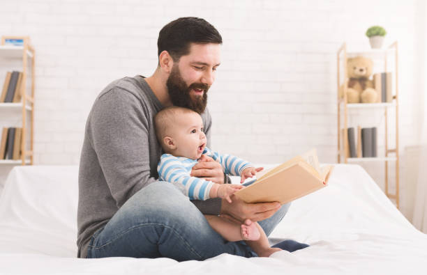 istock Father reading book to little baby son 1087556990