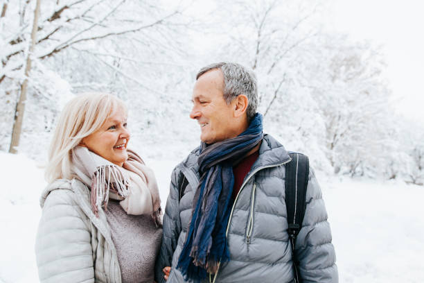 dojrzała para ciesząc się zimową krainą czarów - senior couple senior adult walking action zdjęcia i obrazy z banku zdjęć