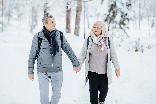 Happy mature couple enjoying the outdoors during winter season at the snowy park